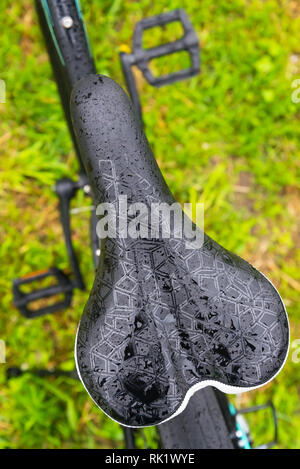 Nahaufnahme eines nassen Fahrrad nach Regen von Mountain Bike. Auf grünem Gras Hintergrund. Stockfoto