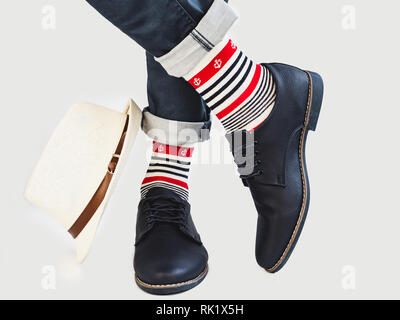 Die Beine der Männer, Helle, bunte Socken mit einem nautischen Thema, Hut und Schuhe auf einem weißen Hintergrund, isoliert. Konzept der Stil, Mode, Eleganz und b Stockfoto