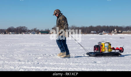 Fair Haven, Michigan - Ein Eis Fischer hols Eis Fanggeräte in Anchor Bay am Lake St. Clair eingefroren. Stockfoto