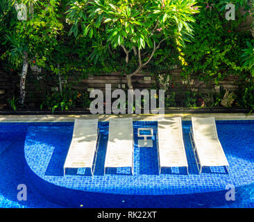 Liegestühle im Schwimmbad von Jimbaran Bay Beach Resort & Spa, Bali, Indonesien. Stockfoto