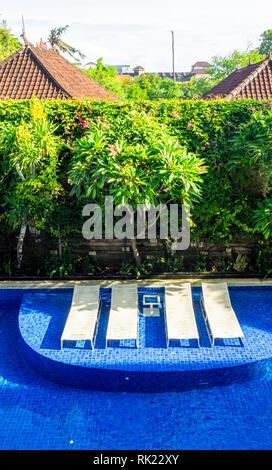 Liegestühle im Schwimmbad von Jimbaran Bay Beach Resort & Spa, Bali, Indonesien. Stockfoto