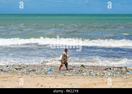 Umweltverschmutzung, einsame Mann herauf Kunststoff Flaschen, Becher, Strohhalme und sonstigem Abfall bis auf den Strand gespült an der Jimbaran Bay, Bali Indonesien.. Stockfoto