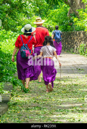 Chinesische Touristen tragen lila Sarongs besuchen Uluwatu Tempel Bali Indonesien. Stockfoto