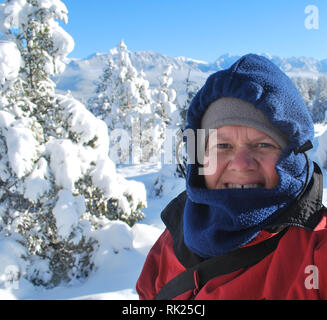 Eine Frau gegen die Kälte im Schnee-bedeckten Wald in den Rocky Mountains von British Columbia, Kanada Stockfoto