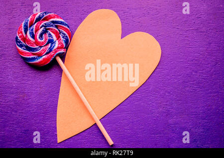 Candy Swirl rainbow Runde zwei Lutscher auf Herzförmigen. Candy Stripes auf einem Stock auf blauem Hintergrund. Liebe Konzept. Februar 14. Urlaub glücklich Valent Stockfoto