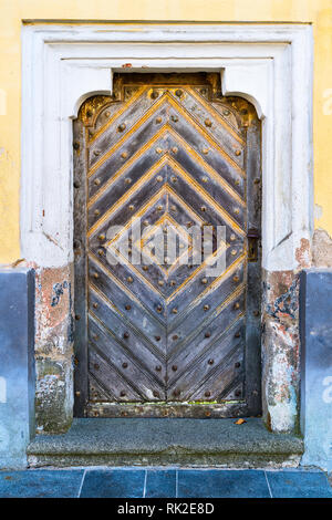 Barocke Tür in einer alten Mauer, dekorative Rahmen und einen Stein vor der Haustür. Vintage Eingang aus massiven Holzbohlen. Klopfer und von rostiges Metall. Stockfoto