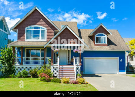 Blaues Wohnhaus mit konkreten Einfahrt in Vorder- und Hintergrund des blauen Himmels. Stockfoto