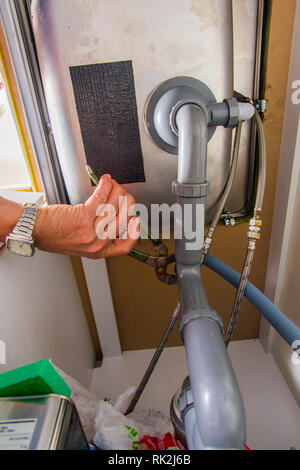 Professionelle Heimwerker arbeitet mit pilers und Befestigung der Leitung am Becken Stockfoto