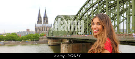 Glücklich lächelnde Frau, die ihre Reisen in Deutschland genießen. Schöne traveler Girl posiert vor der Kamera mit dem Kölner Dom und Hohenzollern Brid Stockfoto