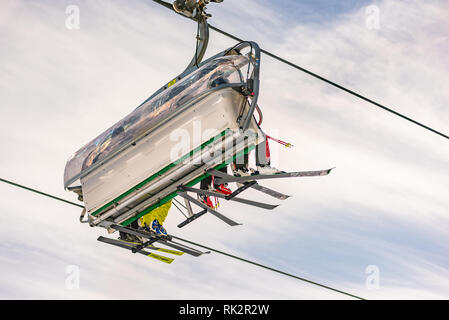 Vier Skifahrer auf einem Sessellift gegen den blauen Himmel, von unten gesehen, von der Skipiste. Skigebiet Schladming Dachstein, Steiermark, Österreich Stockfoto