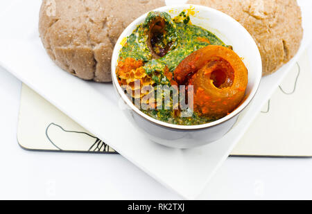 Beliebte nigerianischen Mahlzeiten - Nahaufnahme von Ewedu Gbegiri und verschiedene Fleisch, Suppe mit Amala in einem weißen Teller serviert Stockfoto