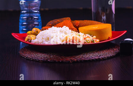 Beliebte nigerianischen Mahlzeiten - eine Nahaufnahme von einer Platte mit weißer Reis, Dodo, Moi-Moi, Salat und Fleisch. Stockfoto