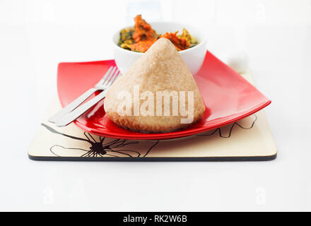Beliebte nigerianischen Mahlzeiten - Egusi Suppe und Weizen essen in einen roten Teller serviert und eine weiße Schüssel Stockfoto