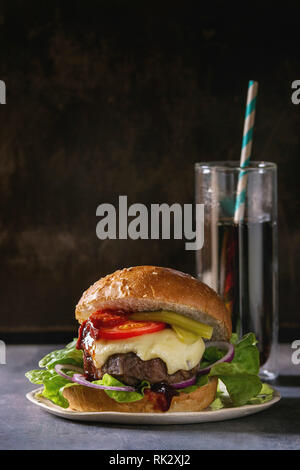 Nahaufnahme von hausgemachten Classic Burger in Weizen Brötchen mit Rind- und Kalbfleisch Schnitzel, geschmolzenem Käse und Gemüse auf weißer Keramik Platte über dunkle Tabelle. Kopieren Stockfoto