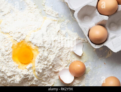 Ein rohes Ei auf einem Hügel von Mehl und Eier in einer Faltschachtel. Stockfoto