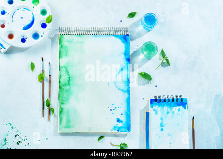 Malerei Frühling Konzept mit Artist Tools, Grün und Blau aquarell Skizzenbücher, Pinsel und Farbpalette auf einen weißen Hintergrund mit Kopie Raum Stockfoto