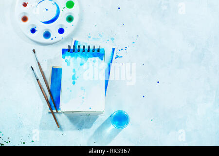 Malerei Frühling Konzept mit Artist Tools, Grün und Blau aquarell Skizzenbücher, Pinsel und Farbpalette auf einen weißen Hintergrund mit Kopie Raum Stockfoto