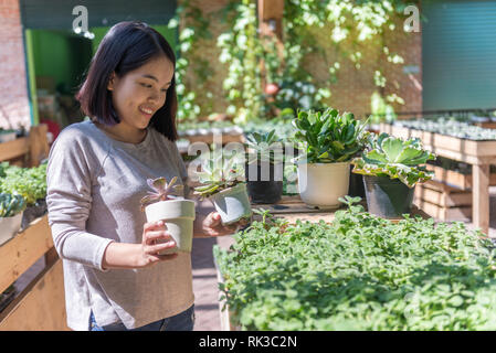 Asiatische Frau wählen Blumentopf in Garten Center Stockfoto