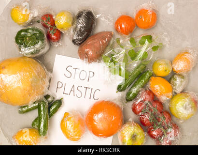 Viele verschiedene Früchte und Gemüse sind in Kunststofffolie verpackte, auf konkreten Hintergrund verpackt Stockfoto