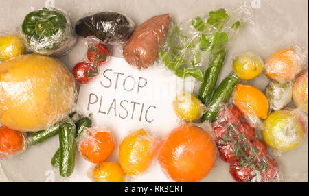 Viele verschiedene Früchte und Gemüse sind in Kunststofffolie verpackte, auf konkreten Hintergrund verpackt Stockfoto