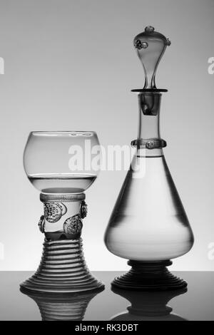 Mittleres Alter rummer Wein Glas und Flasche auf dem weißen Hintergrund. Schwarzweiß, Schwarzweiß-Bild. Stockfoto