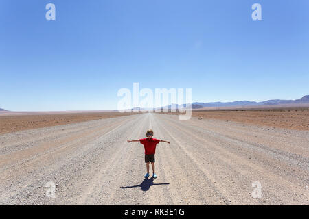 Junge Ausweitung der Arme auf eine typische Straße in Namibia Stockfoto