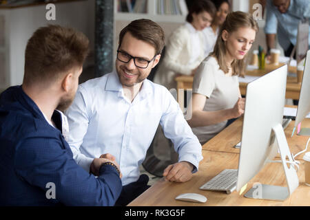 Freundlich glückliche Mitarbeiter handshaking Kollegen am Arbeitsplatz Dank für Hilfe Stockfoto