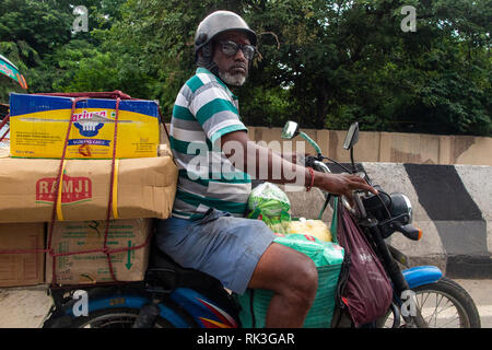 Ein Mann mit Brille und seine Einkaufsmöglichkeiten auf der Rückseite seines Motorrad in Chennai, Südindien Stockfoto