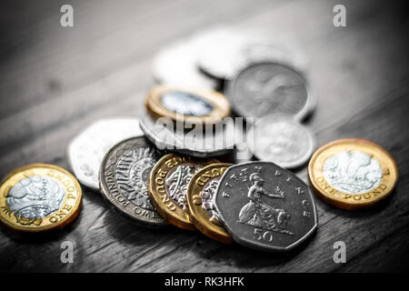 Neues Britisches Pfund GBP Münzen Festlegung beiläufig auf schwarze Brieftasche auf Holz- Oberfläche. Reichtum, Geld, Bargeld, ändern. Stockfoto