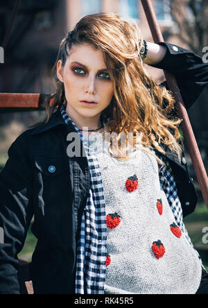 Outdoor Portrait des schönen Grunge (Rock) Mädchen in Jeans Jacke, kariertem Hemd und Pullover Stockfoto