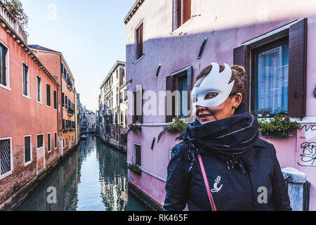 Venedig, Italien - 10 Februar 2018: Maskierte junge Frau mit einem typisch Venedig Canal im Hintergrund Stockfoto