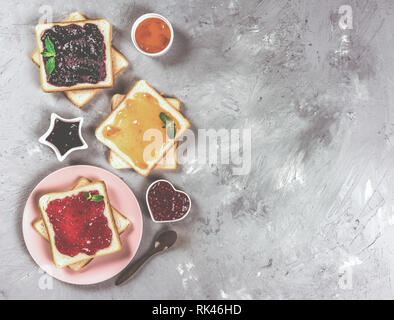 Leckere Toasts mit verschiedenen süßen Marmeladen auf grauem Hintergrund. Copyspace für Ihren Text, Banner Stockfoto