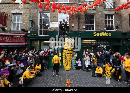 Ein chinesischer Lion steigt Salat aus eine Angelschnur zu holen, es zu essen, was kennzeichnet einen neuen Beginn, am SeeWoo shop in Lisle Street Während eines Pre-Chinese New Year Celebration in Chinatown, London, vor der dieses Wochenende chinesische Neujahrsfest am Sonntag, die das Jahr des Schweins. Stockfoto