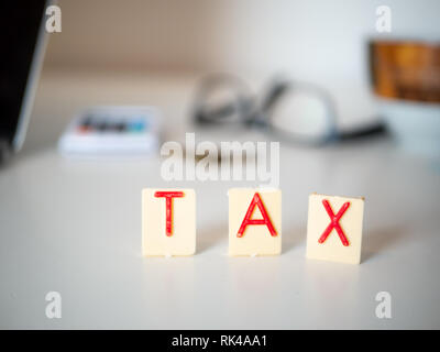 Weiß Schreibtisch mit Dokumenten, Gläser, Rechner und Notebook, Buchstaben sagen "Steuer" Stockfoto