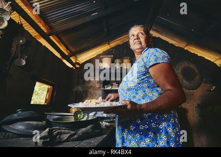 Ländliche Frau Zubereitung von Speisen in der traditionellen Küche zu Hause. Das häusliche Leben in Sri Lanka. Stockfoto