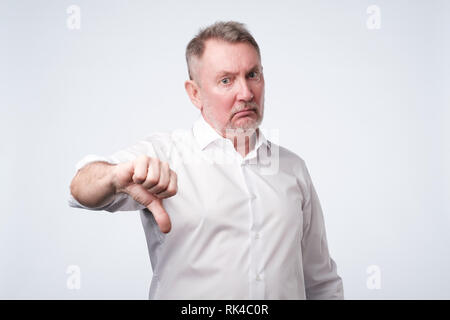 Älterer Mann im weißen Hemd mit Daumen nach unten Stockfoto
