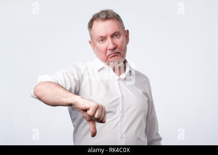Älterer Mann im weißen Hemd mit Daumen nach unten Stockfoto