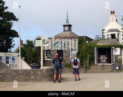 Zwei Männer Wanderer an der hölzernen Wegweiser auf der Straße in das Dorf in der Mitte der Insel Sark, Kanalinseln, Großbritannien. Stockfoto