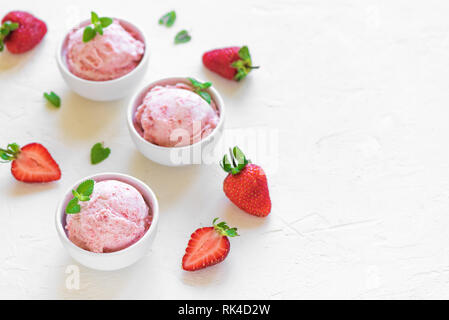 Erdbeereis und frische Erdbeeren auf weißem Hintergrund, Ansicht von oben. Drei Becher Erdbeereis, gesunden Sommer Nachtisch. Stockfoto