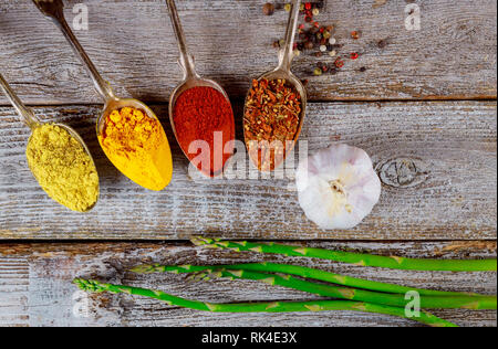 Verschiedene Gewürze in Löffel auf alten Holztisch, Ansicht von oben Stockfoto