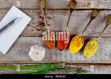 Verschiedene Gewürze Knoblauch und Spargel in vintage Löffel auf alten Holz Hintergrund Stockfoto