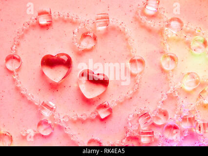 Transparente Herzen und Perlen auf Marmor in rosa Ton. Perfekte Valentinstag Grußkarte Hintergrund. Stockfoto