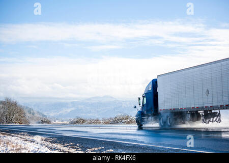 Big Rig pro Long Haul blue Semi Truck Traktor Transport von kommerziellen Ladung im Kühlschrank Auflieger gehen auf das Nass glänzende Straße mit Wasser aus Stockfoto