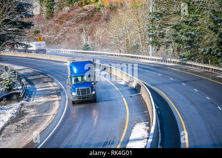 Big Rig pro Long Haul blue Semi Truck Traktor Transport von kommerziellen Ladung im Kühlschrank Auflieger gehen auf das Nass glänzende Straße mit Wasser aus Stockfoto