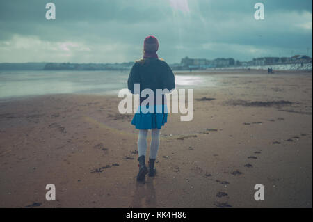 Eine junge Frau wird zu Fuß am Strand im Winter Stockfoto