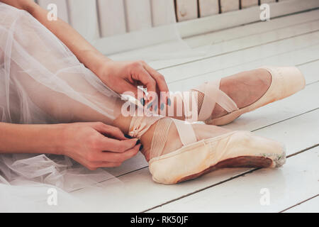 Die Authentische ballerina Ballett Tänzerin sitzen auf dem Boden und binden Spitzenschuhe, in der Nähe Stockfoto