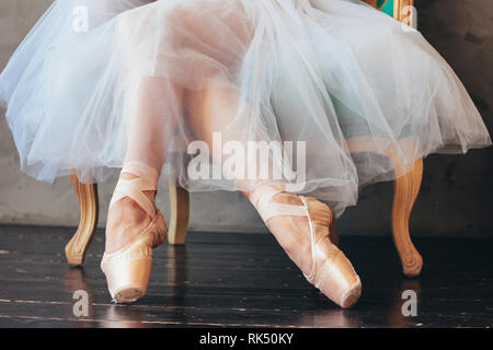 Die Ballerina Ballett Tänzerin in Tutu Rock und Pointe shous sitzen auf dem klassischer Stuhl Stockfoto