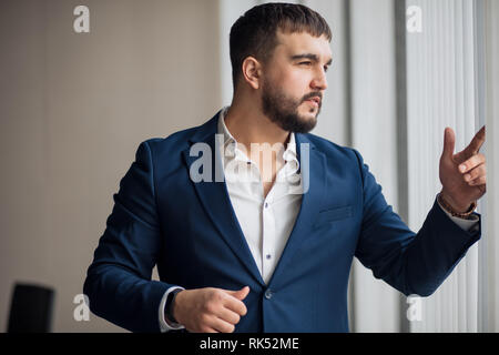 Zuversichtlich lächelnd nach steht und schauen durch das Fenster. Bis schließen Seitenansicht Foto. im Büro, im Freien. Stockfoto