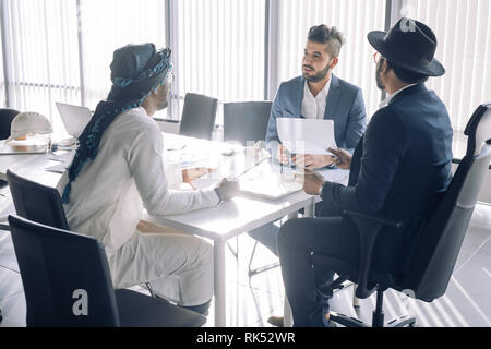 Multiethnische Gruppe zuversichtlich konzentrierte sich Experten analysiert Ergebnis am Tisch sitzen in Kunden modernes Büro im Nahen Osten Stockfoto