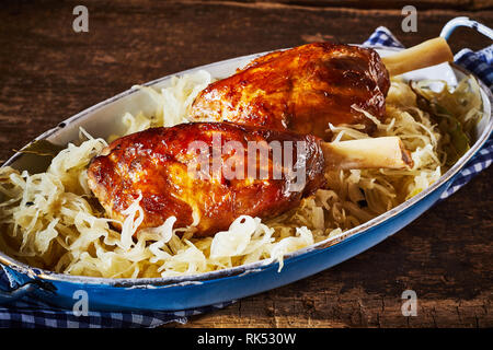 Gebratene eisbein oder Deutsch Schweinshaxen serviert auf einem Bett von zerkleinerte Kohl in ovaler Schale Stockfoto